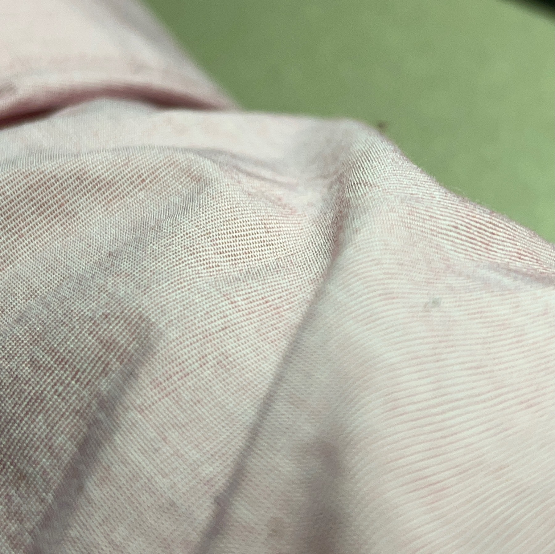 Macro photo of pink poplin fabric of a shirt with some wrinkles in it. 