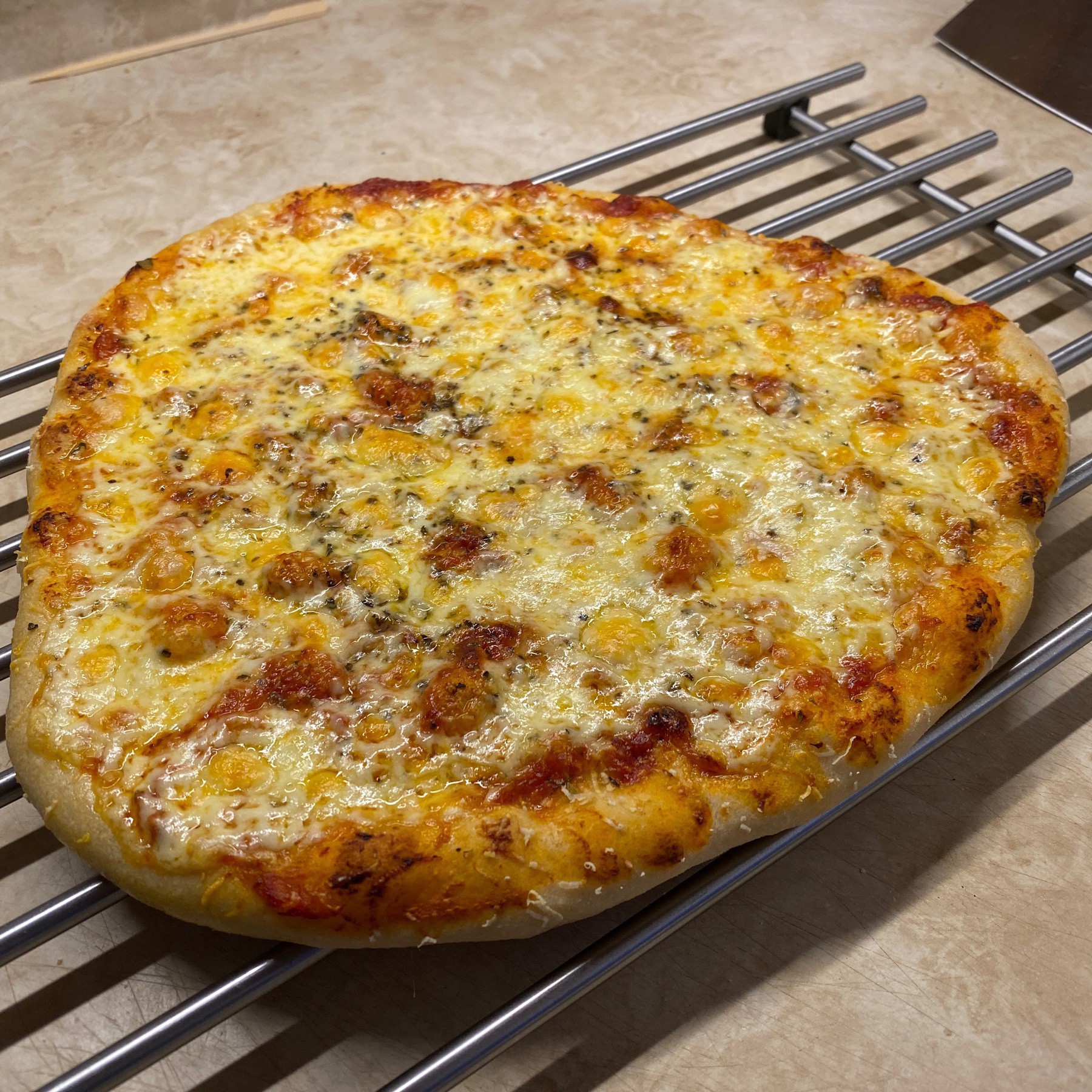 Cheese pizza cooling on rack.