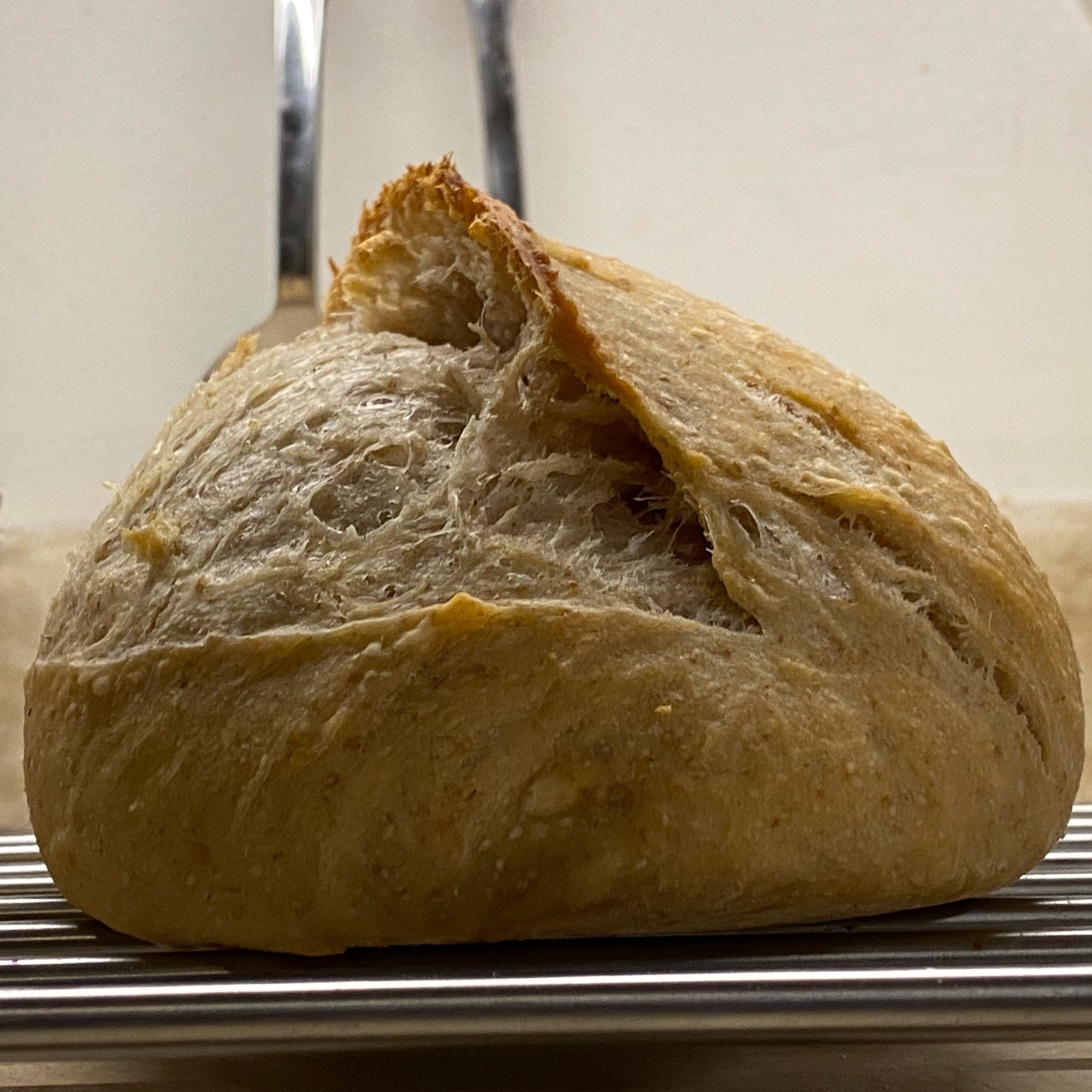 Sourdough loaf from side cooling on rack.
