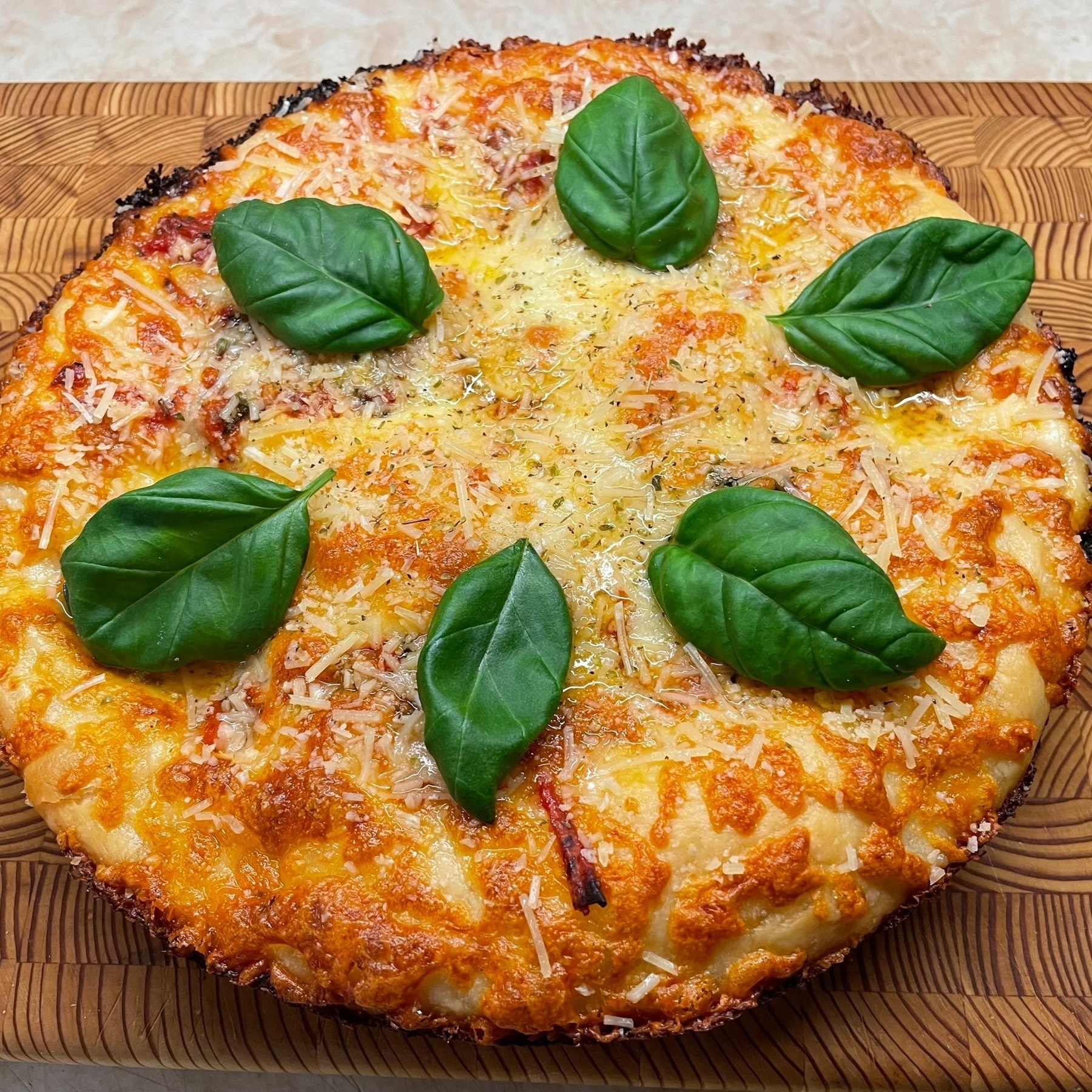 Pizza on cutting board with basil leaves on top.