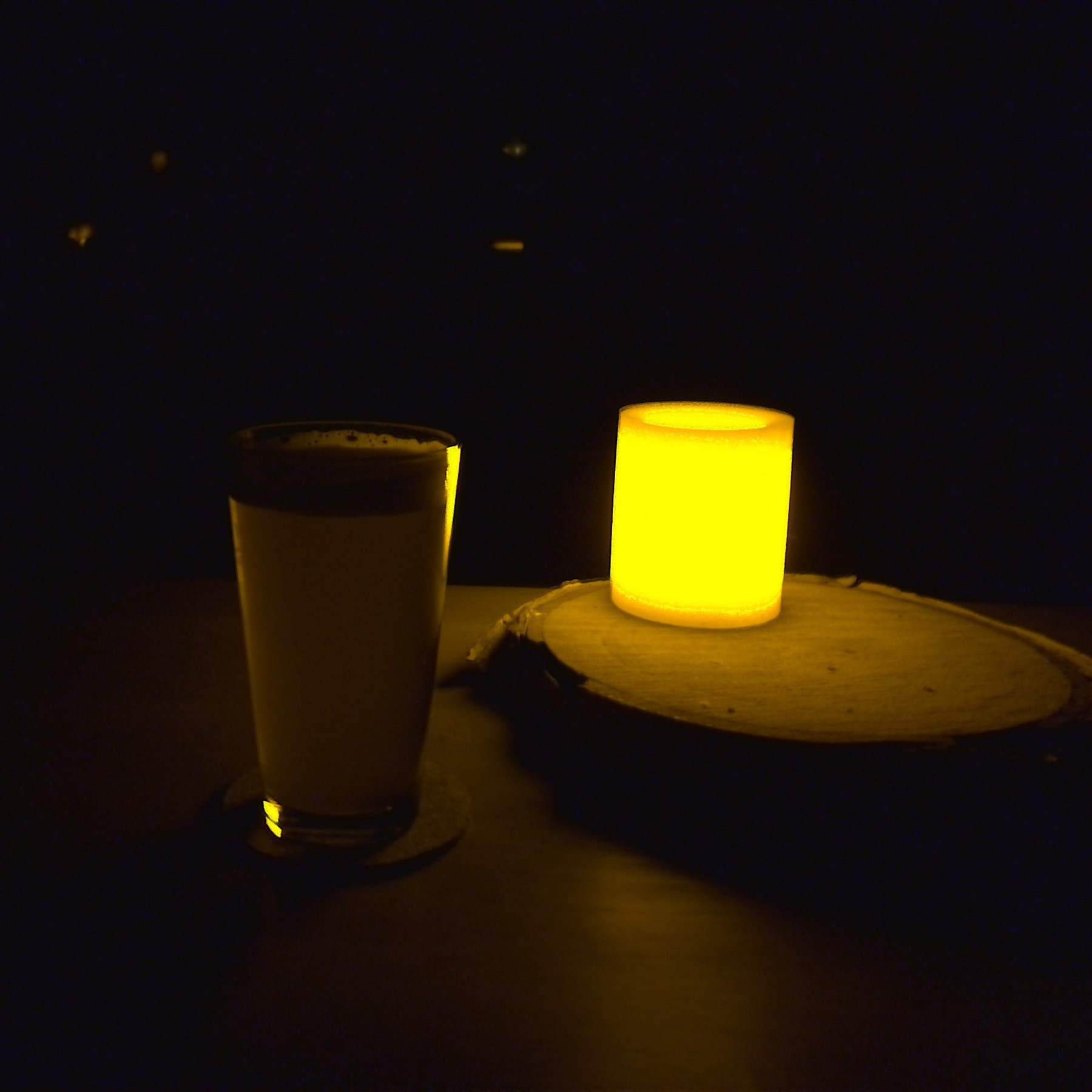 Glass if beer beside LED candle.