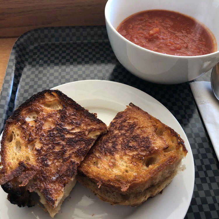 Grilled cheese on plate and bowl of tomato soup.