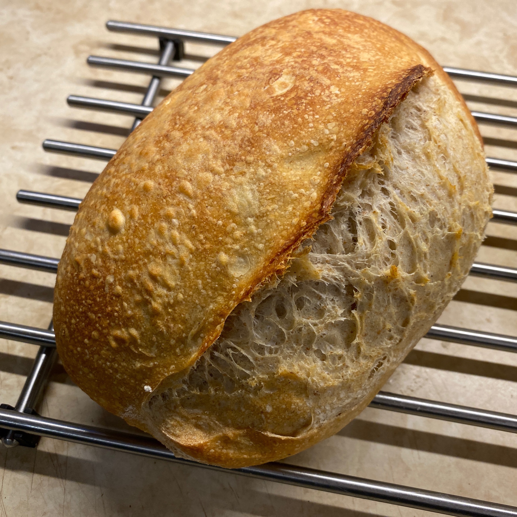 Loaf of sourdough bread on rack.