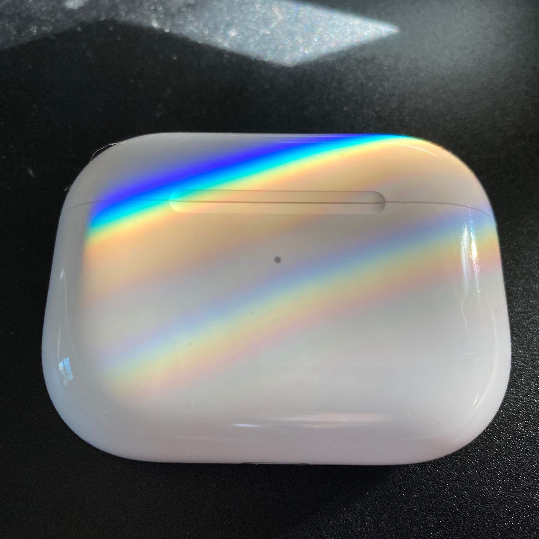 AirPods Pro case with refracted rainbow stripes on it.