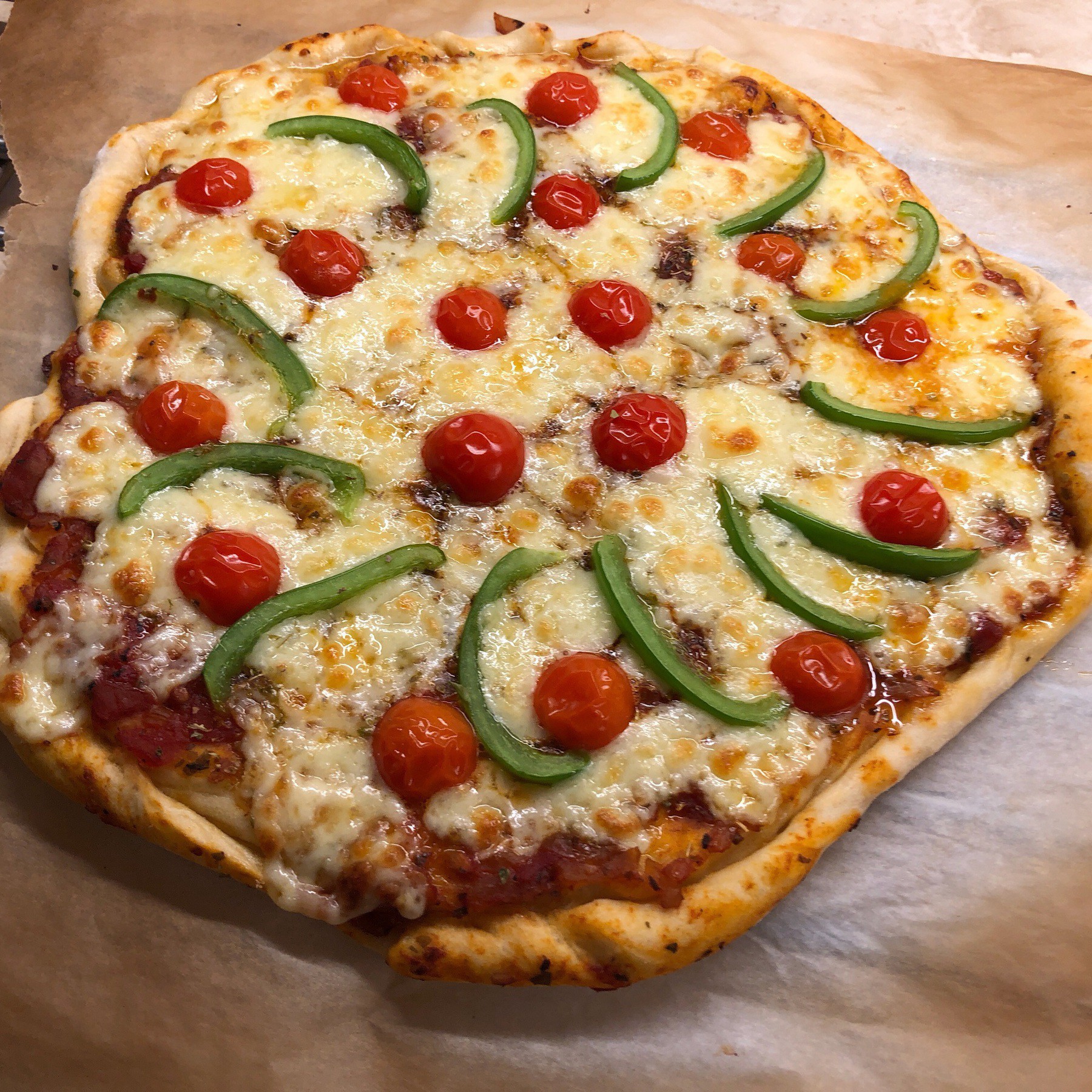 Veggie pizza with tomatoes and green pepper and cheese.