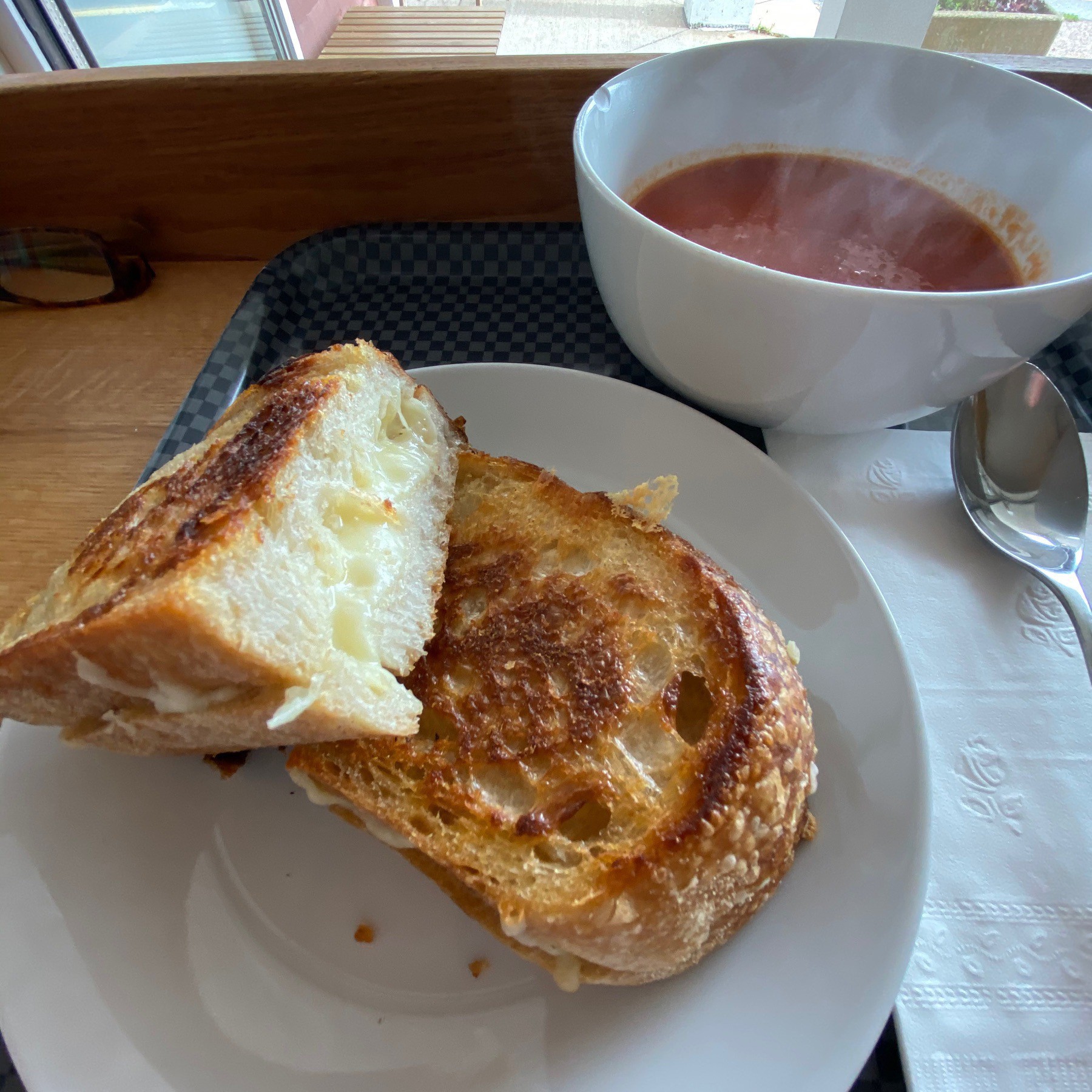 Grilled cheese sandwich on plate with bowl of tomato soup.