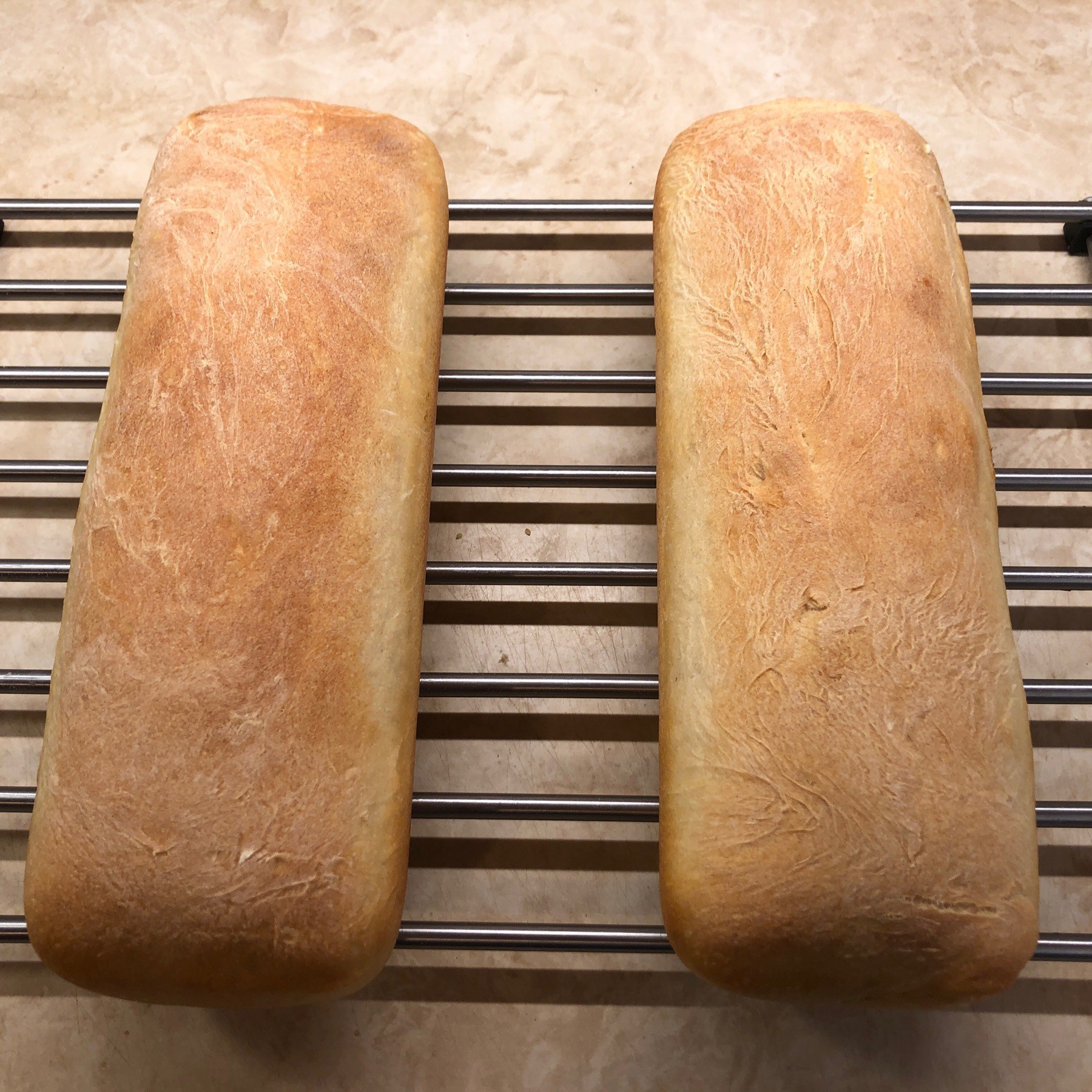 Two loaves of bread on cooling rack.