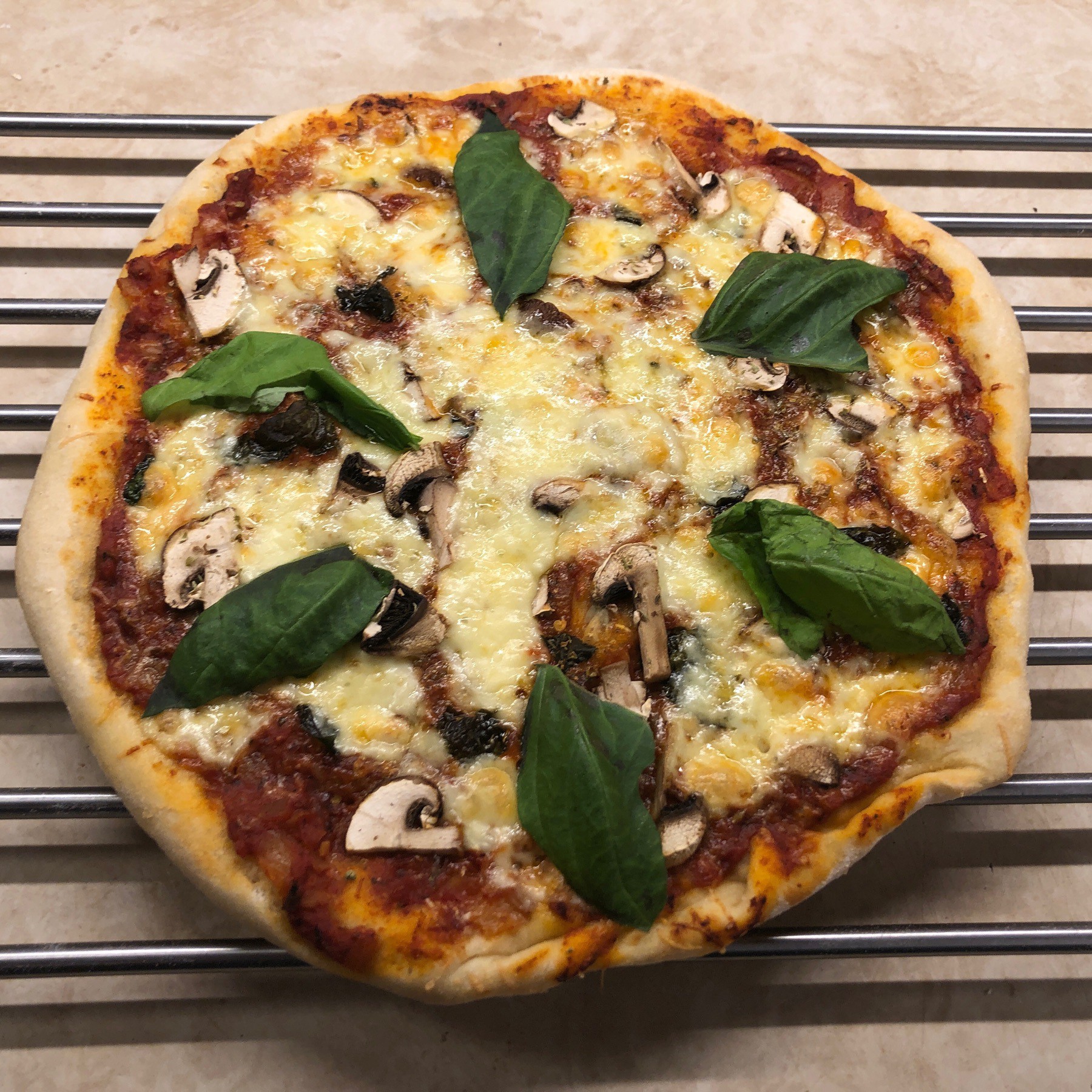 Cheese and mushroom pizza on cooling rack.