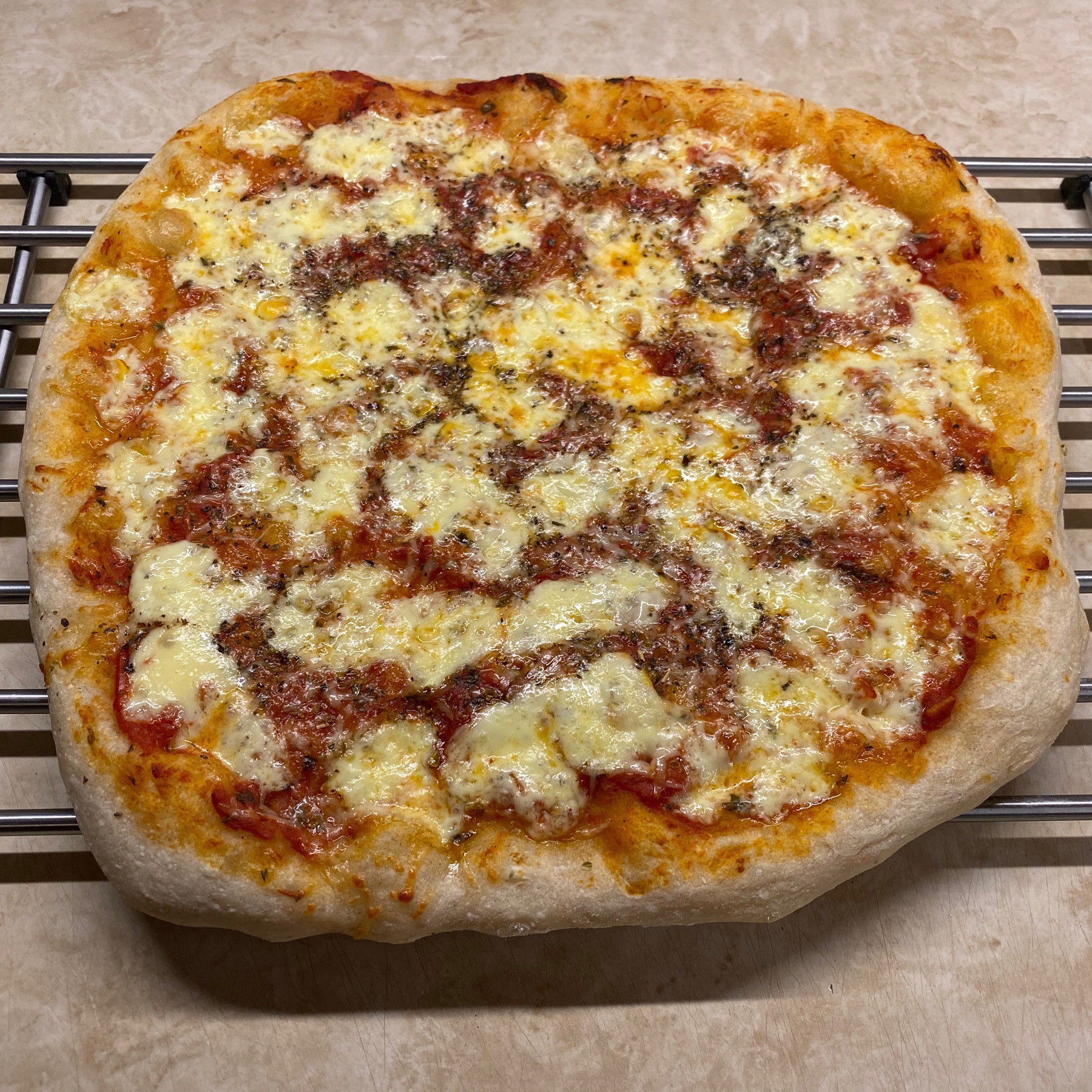 Cheese pizza cooling on rack.