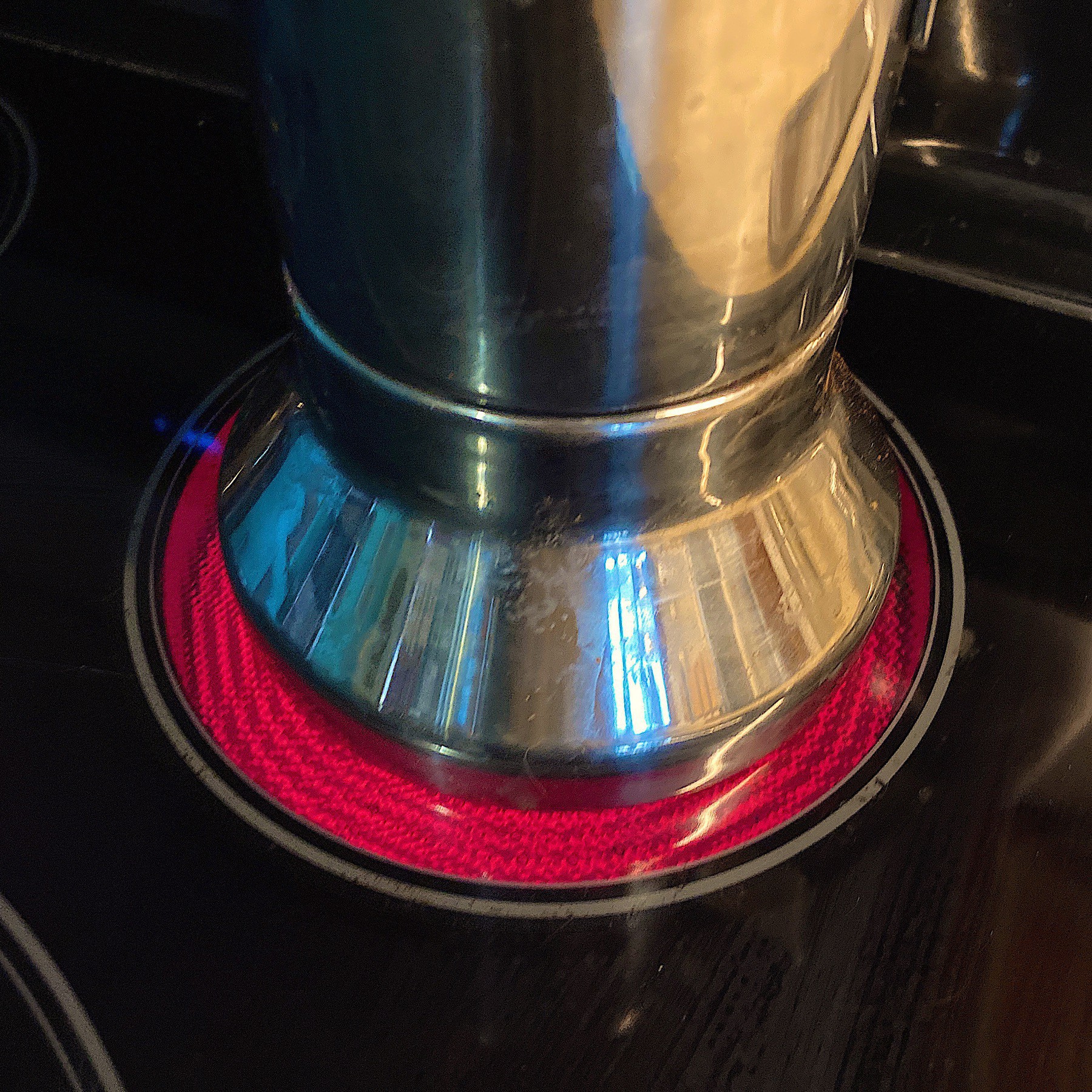Bottom of metal coffee maker on glass stovetop.