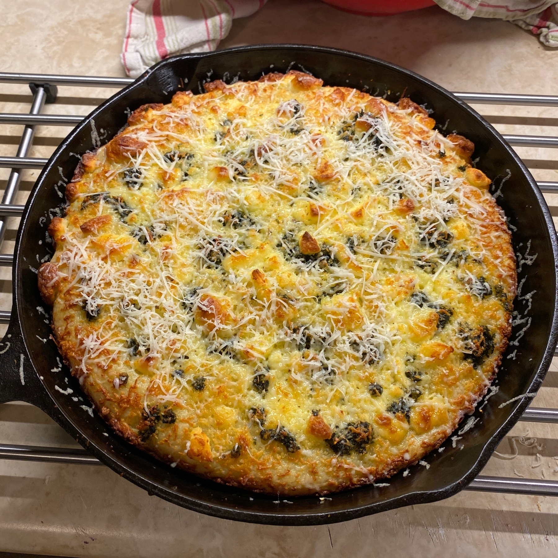 Pizza in cast iron pan on metal rack.