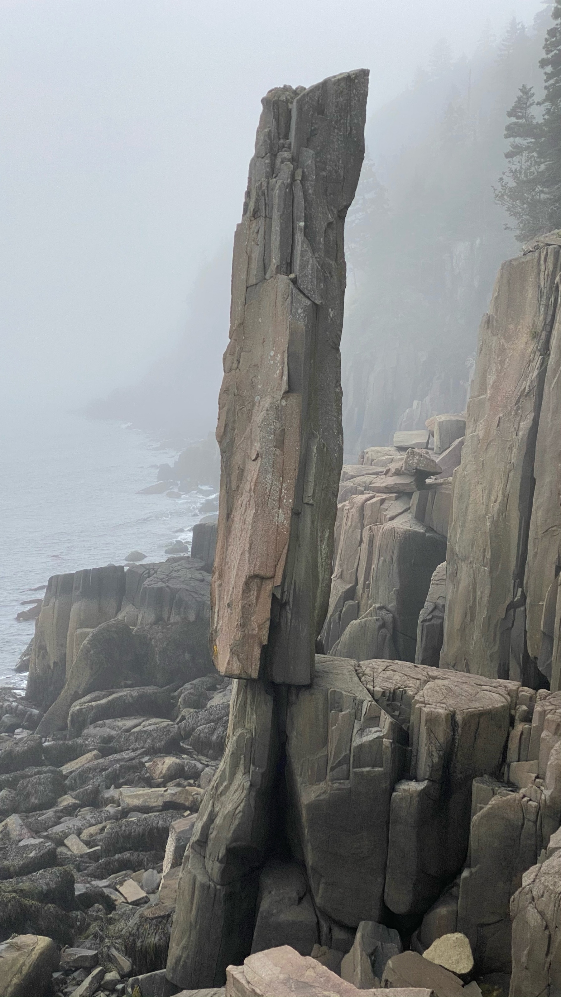 Basalt rock column balancing beside cliff.