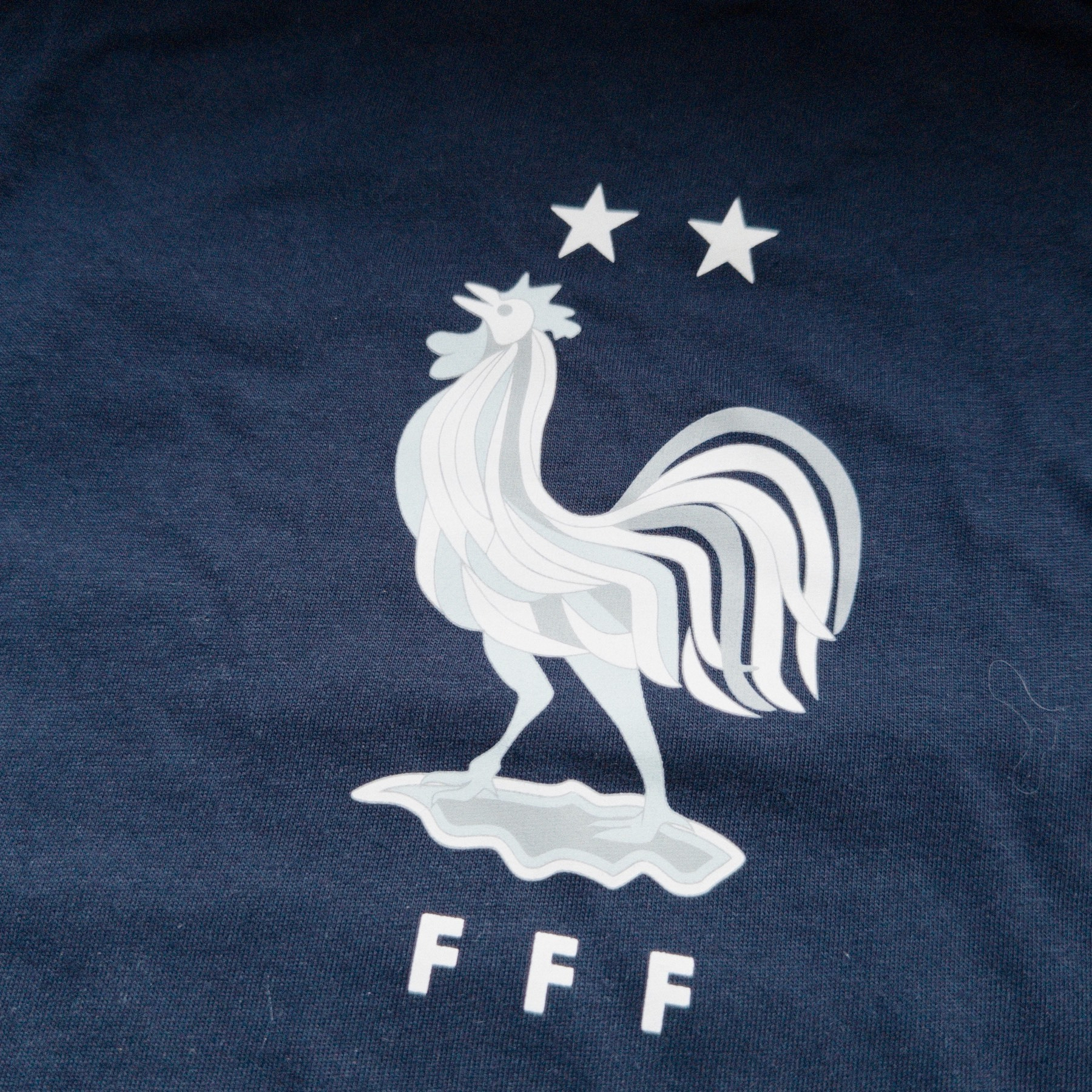 White logo for the French Football Federation on a dark blue t-shirt. 